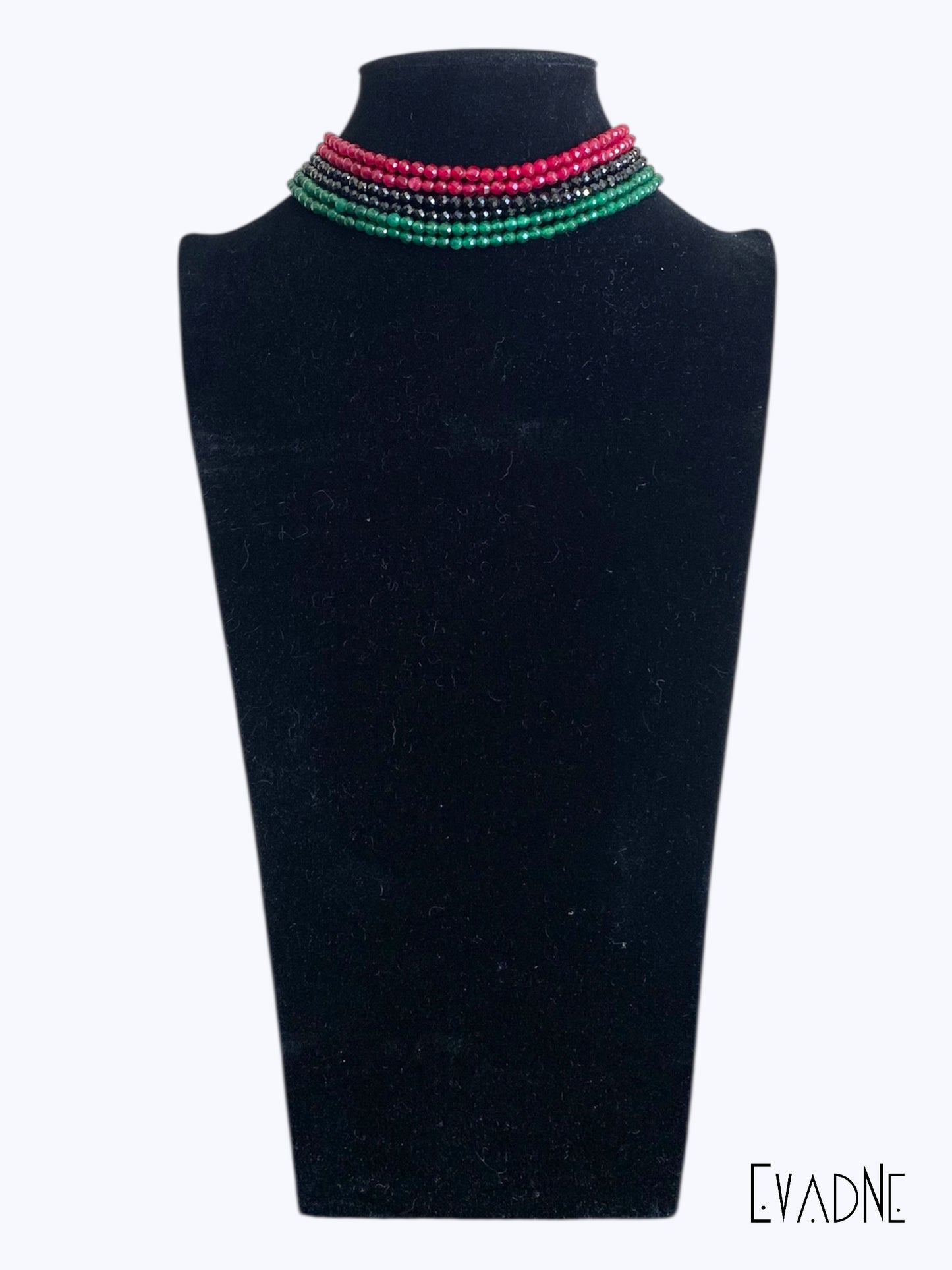 Multi strand Necklace with red, green and black beads on a black mannequin bust, branded 'EVAdNE'.