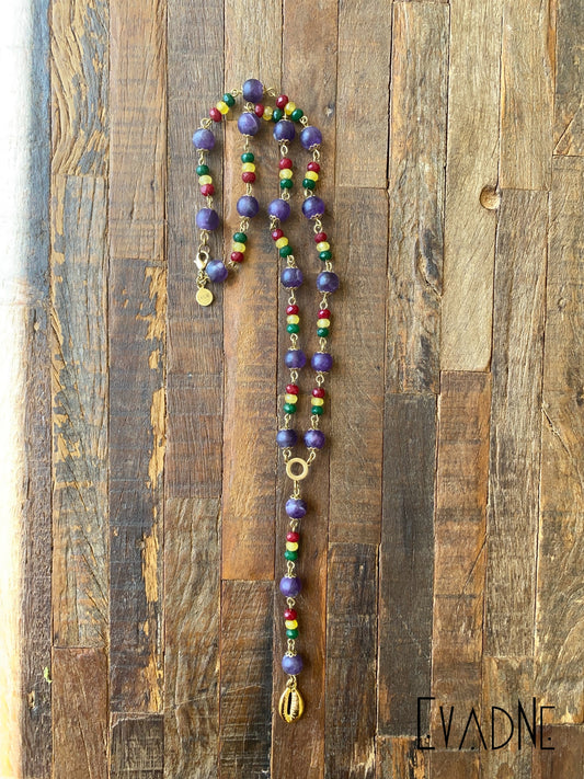Colorful beaded necklace on a wooden background with 'EVADNE' branding.