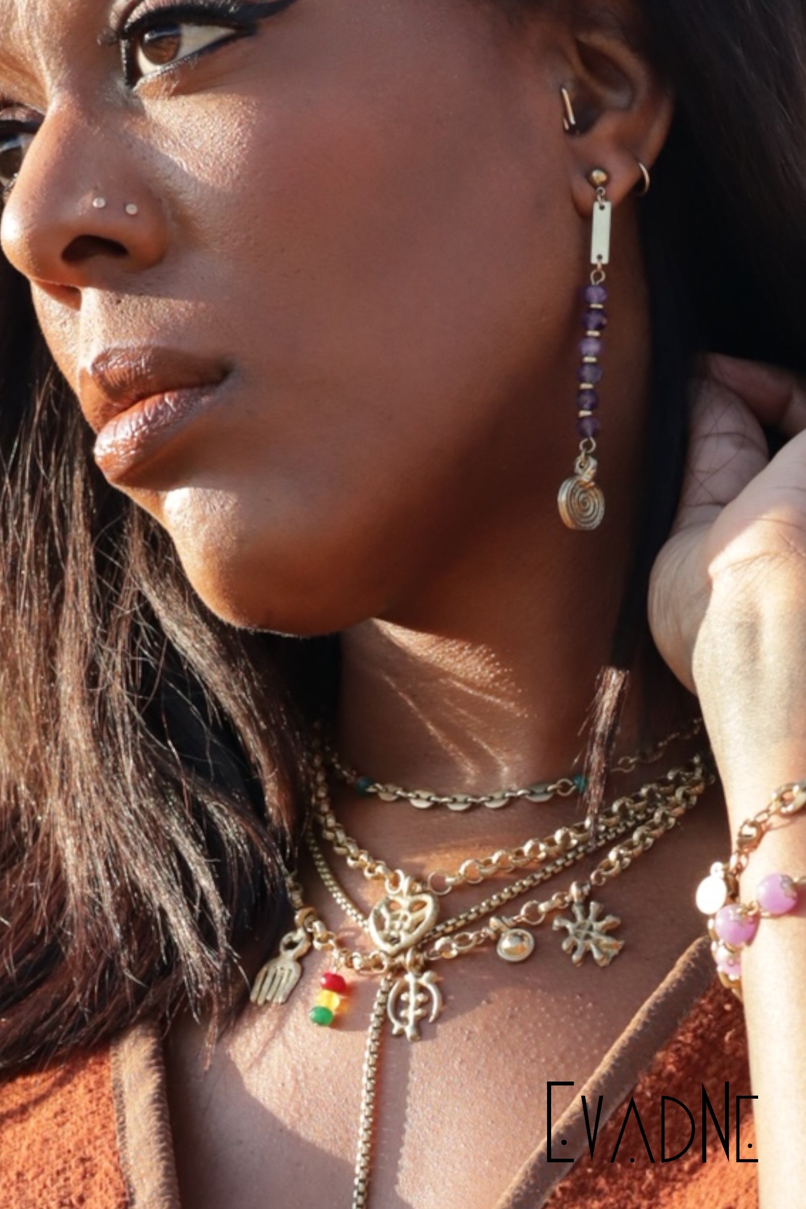 Close-up of a woman wearing multiple necklaces and earrings with a brand name visible.