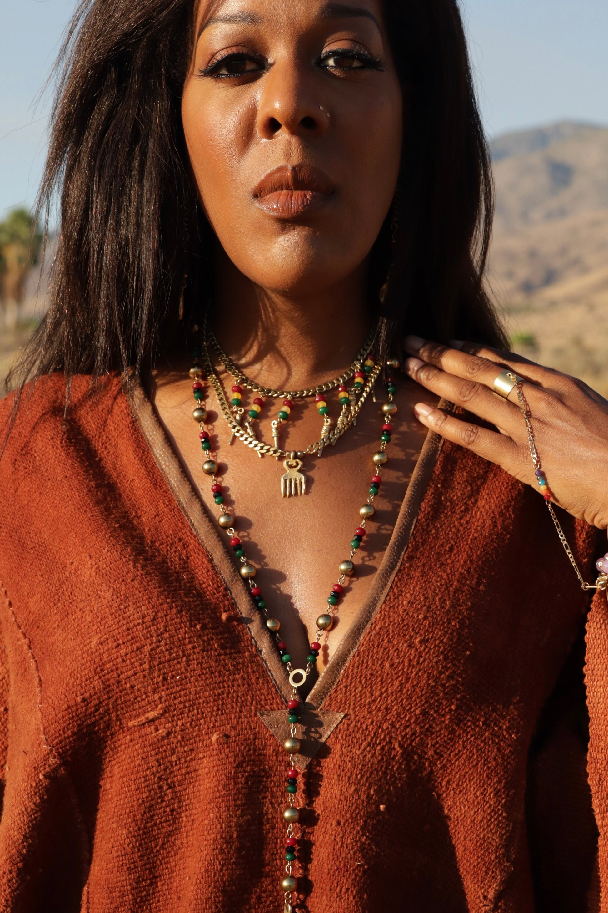 Woman wearing a rust-colored poncho with layered necklaces in a desert setting