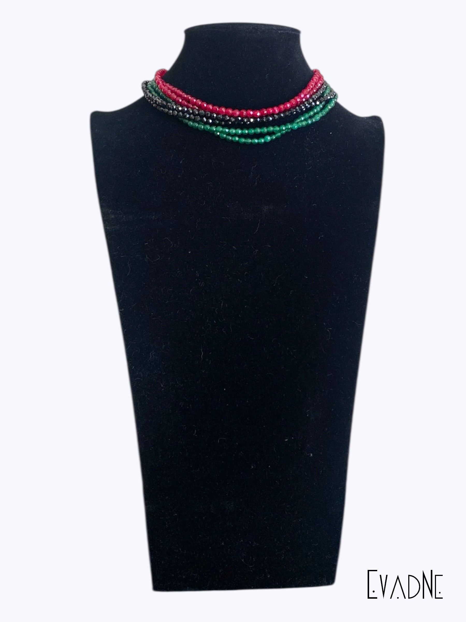Multi strand Necklace with red, green and black beads on a black mannequin bust, branded 'EVAdNE'.