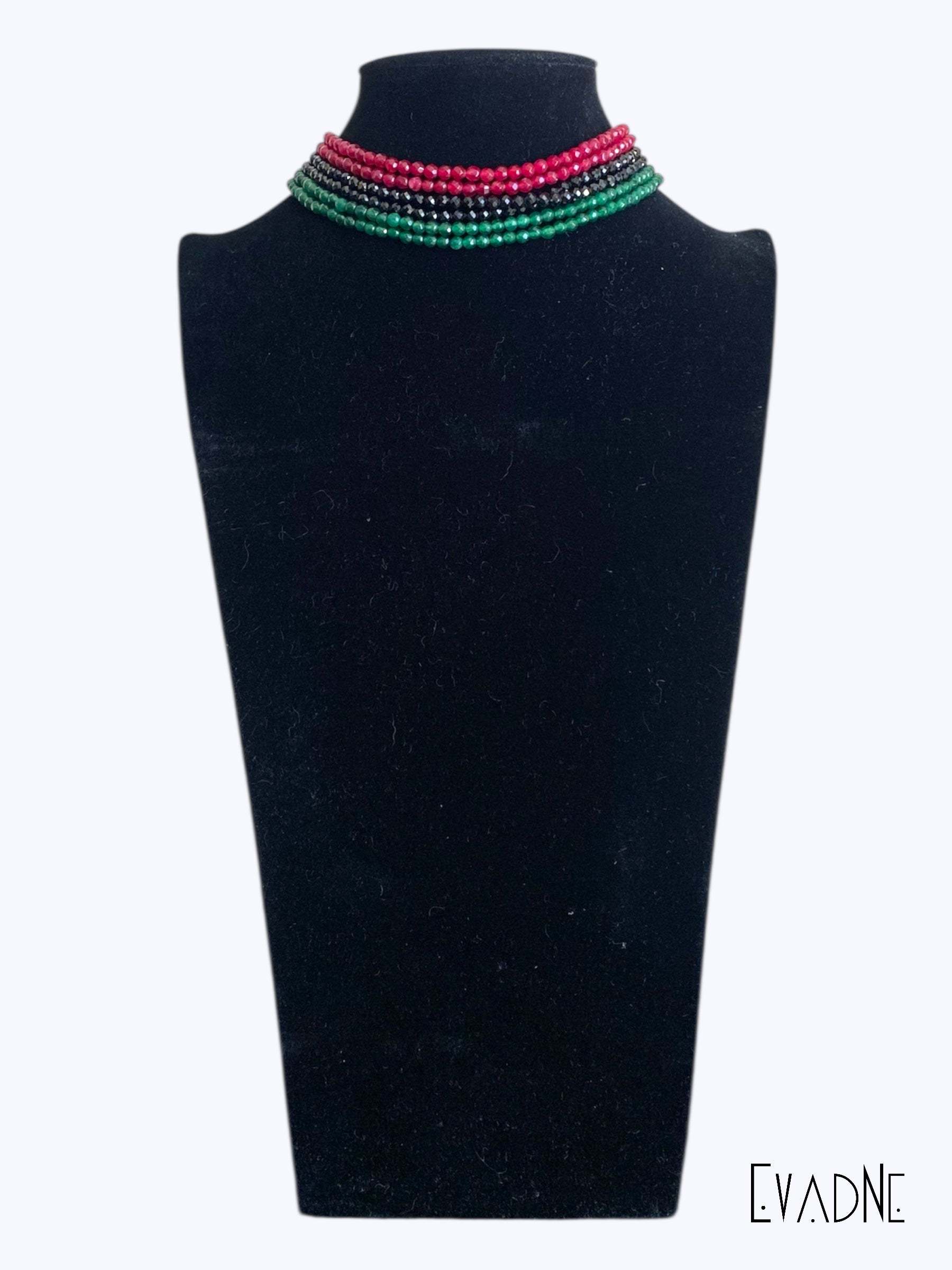 Multi strand Necklace with red, green and black beads on a black mannequin bust, branded 'EVAdNE'.