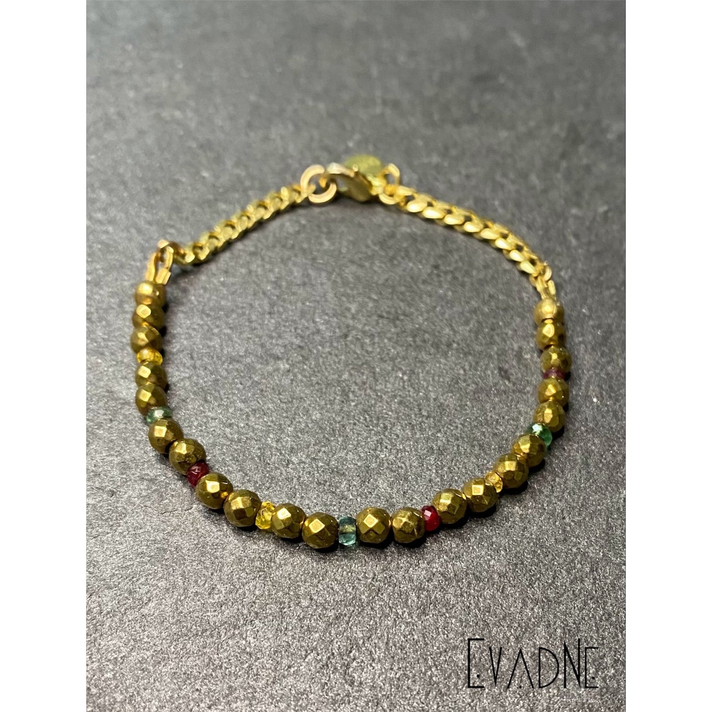 Gold hematite beaded bracelet with emerald, yellow sapphire, and ruby accents and brass Cuban link chain.
