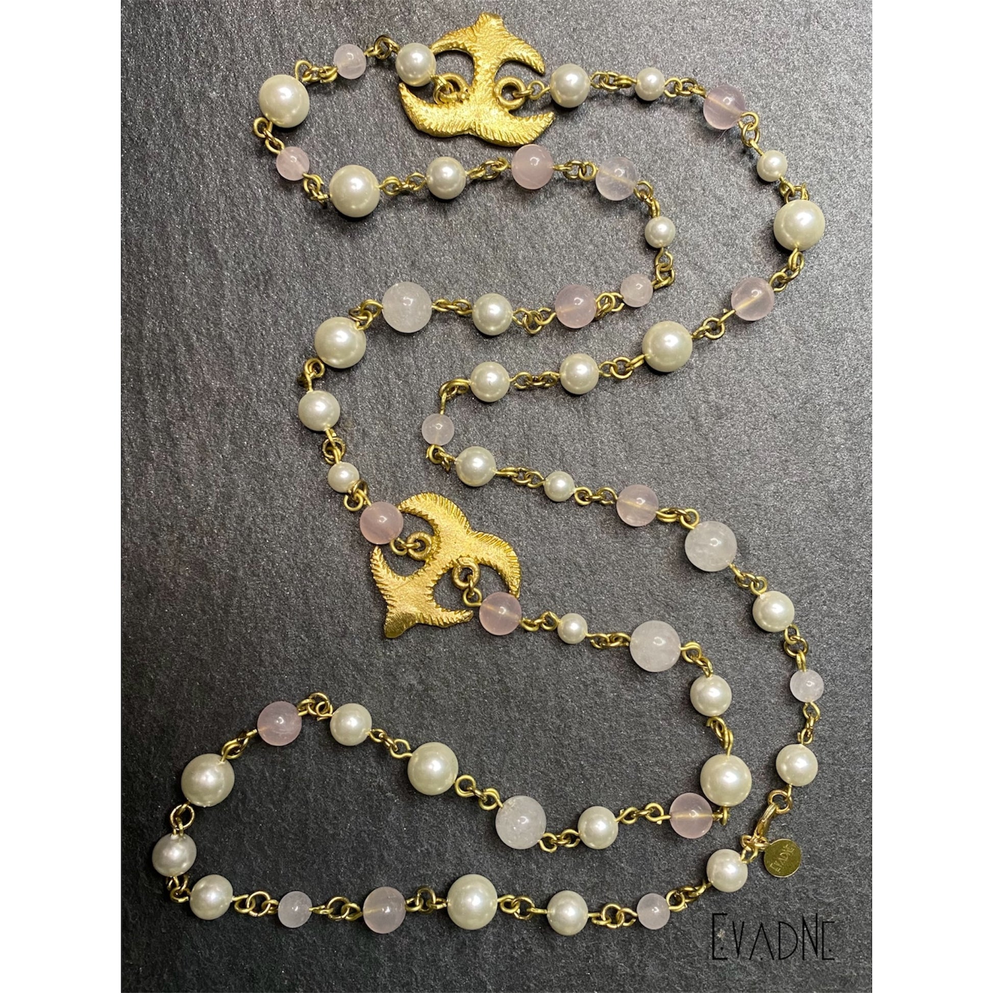 Long pearl and rose quartz necklace with brass Akoko Nan Adinkra symbol, 42-inch strand with faux pearls and pink stone beads.