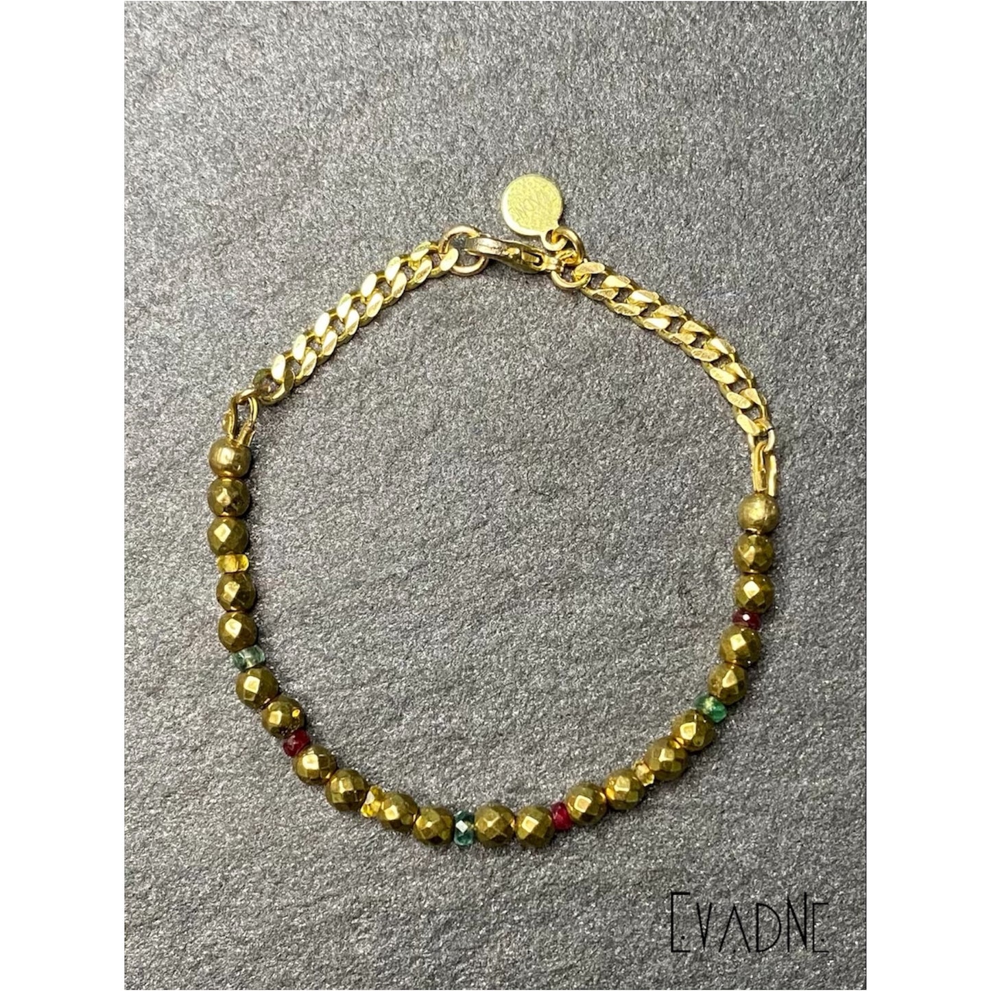 Close-up of faceted gold hematite beads with red, green, and yellow gemstone accents.