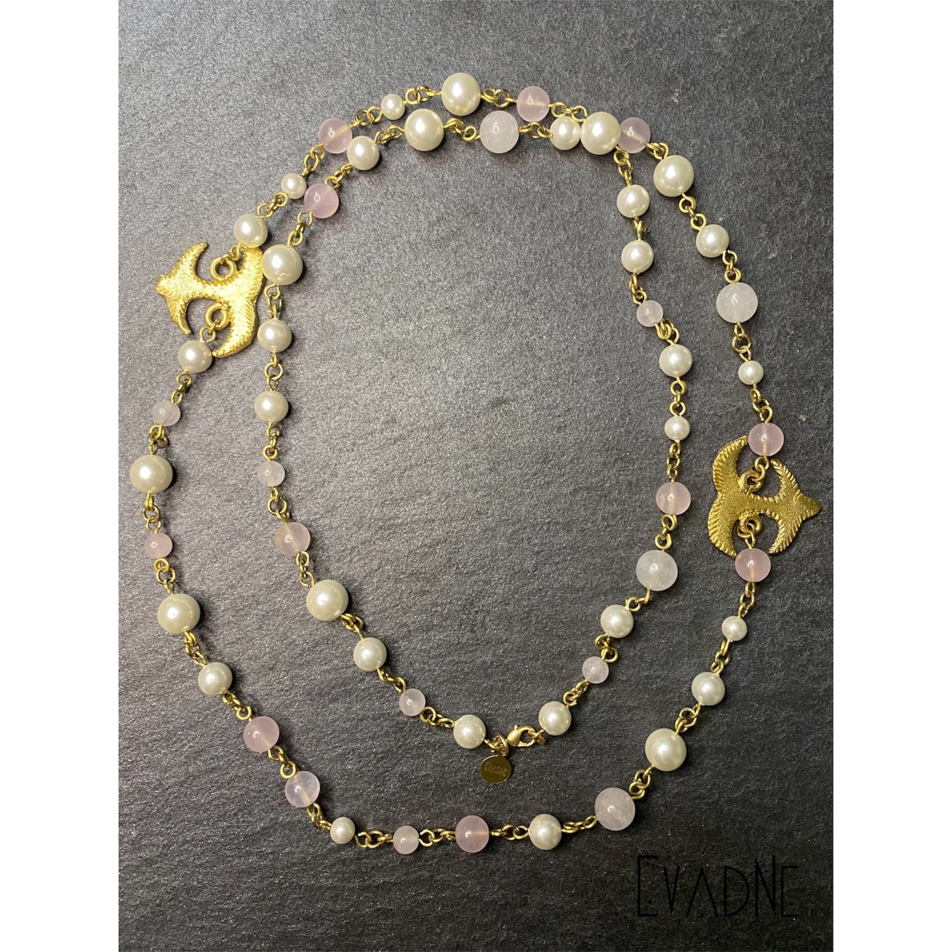 Brass Akoko Nan Adinkra symbol charm attached to pearl and rose quartz beaded necklace.