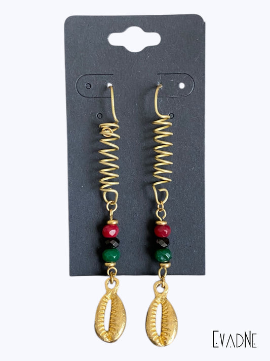 Pair of gold spiral earrings with red, green and black beads and gold cowrie shell on a black card, branded 'EVADNE'.